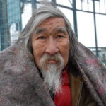 Homeless Native American man facing camera with blanket on his shoulders