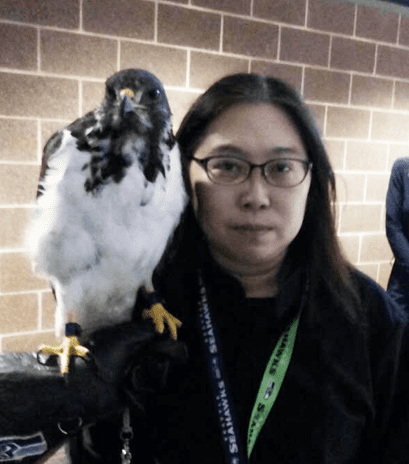 Sze poses for a picture with Seattle Seahwaks mascot Taima the hawk on her shoulder.