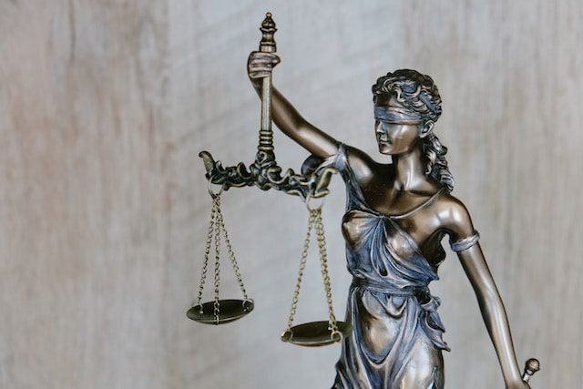 Statue of Lady Justice blindfolded and holding scales and a sword. [Photo by Tingey Injury Law Firm on Unsplash.com]