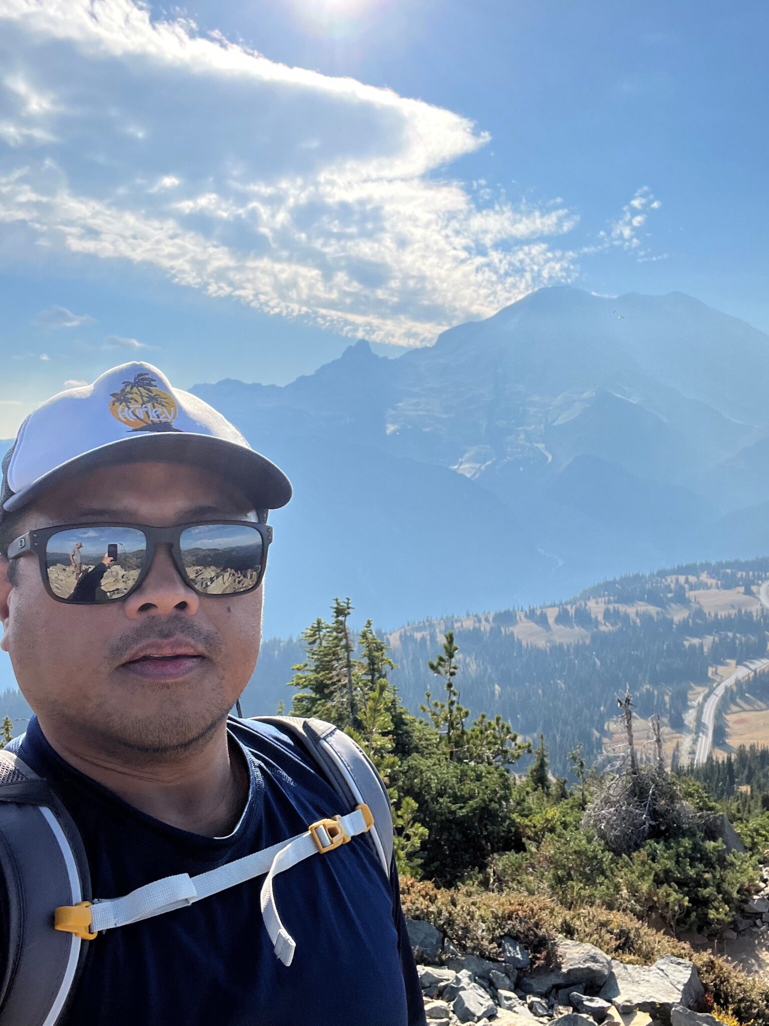 Selfie of Edwin Obras with clouds, distant landscape, and Mount Rainier in the background during a hike.