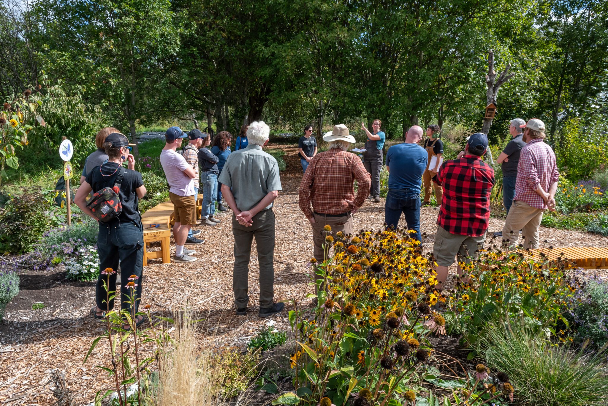 A group of people standing in a circle on a farm path listening to a tour guide