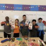 five kids standing in front of a white board holding up prizes from activities held by Atlantic Street Center