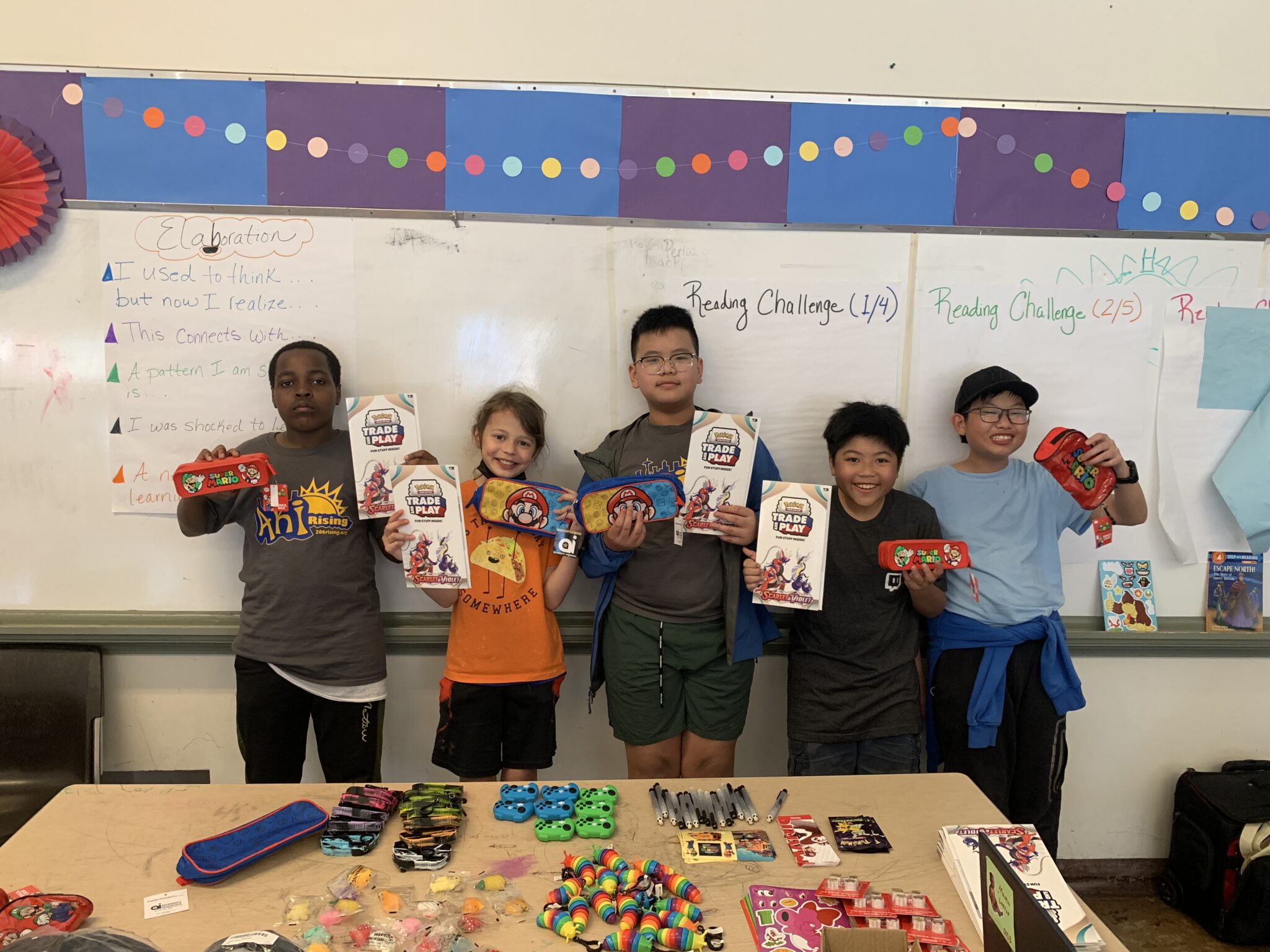 five kids standing in front of a white board holding up prizes from activities held by Atlantic Street Center