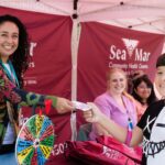 A young boy received a prize after spinning a wheel at a SeaMar information booth.