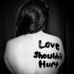 Back of a T-shirt with the words "Love Shouldn't Hurt"