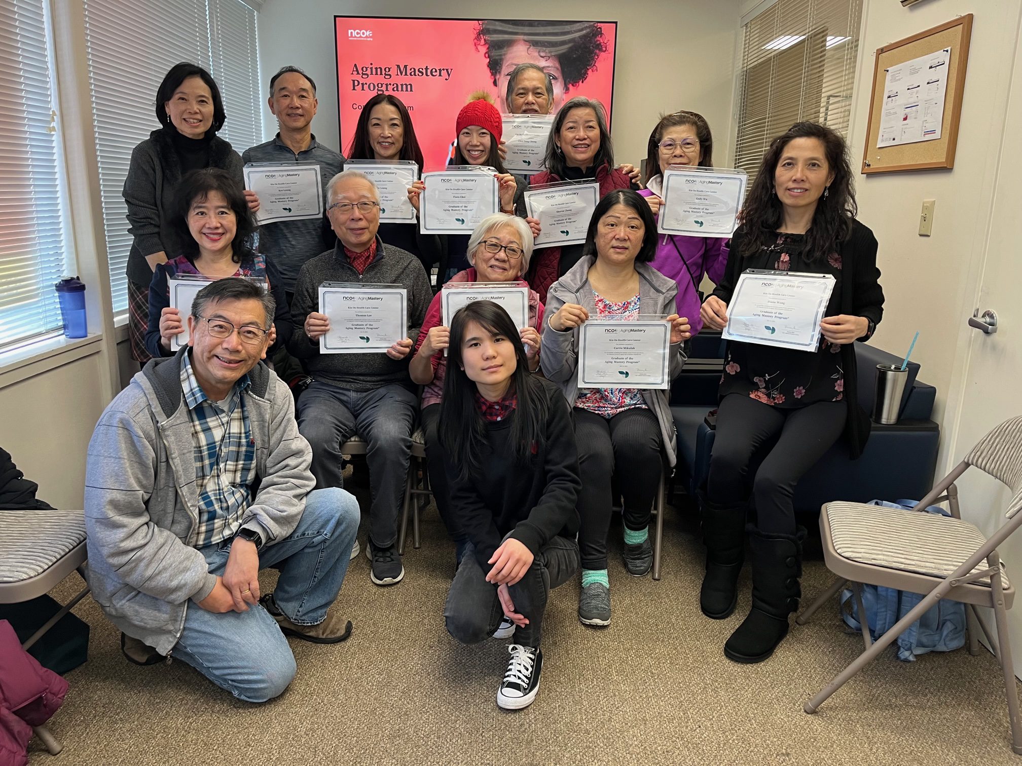 Participants in the Aging Mastery Program hold up certificates of completion for a group photo