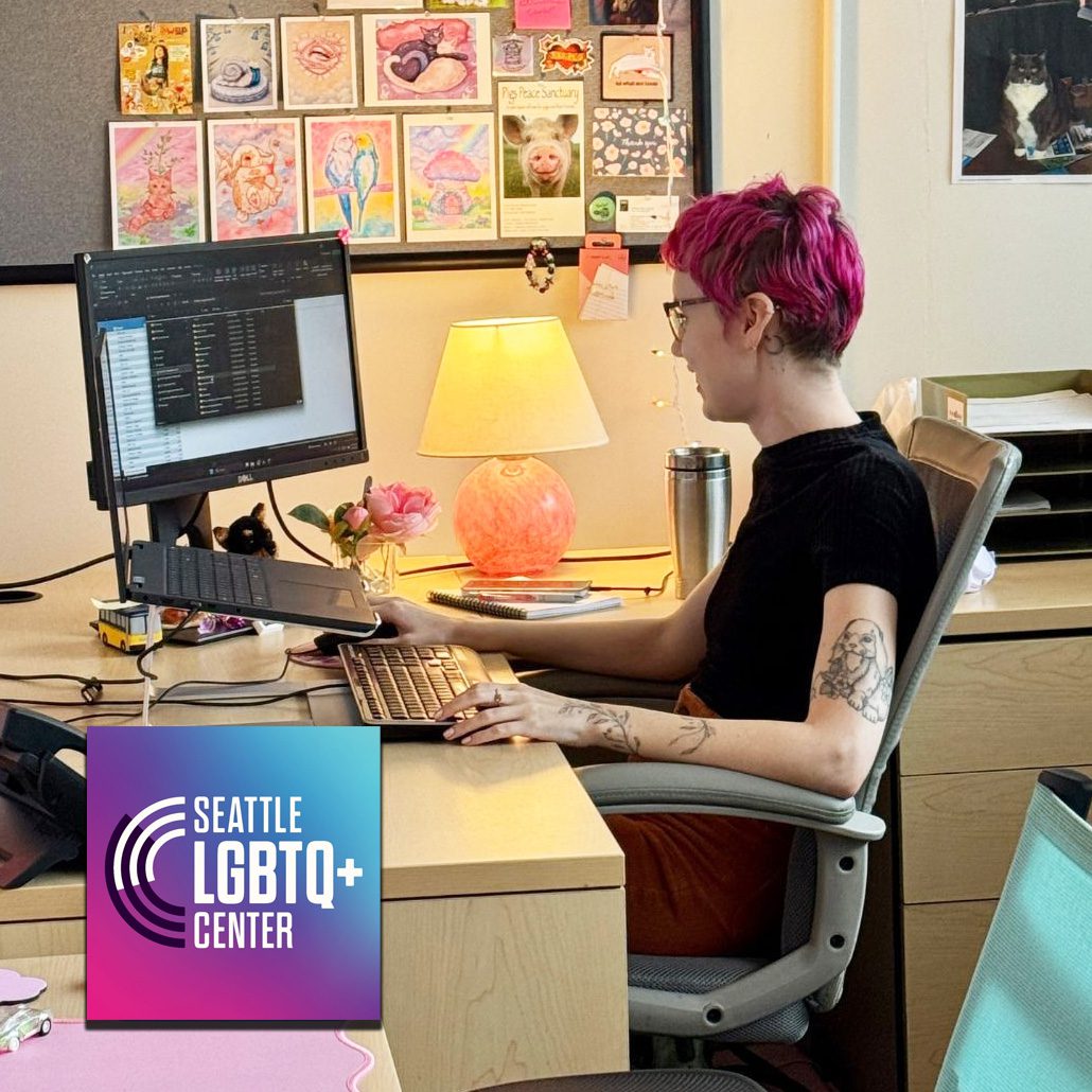 A staff member at the Seattle LGBTQ+ Center sitting at a desk working on a computer.
